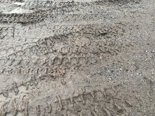 dirty mud road with footprints in the middle of the road