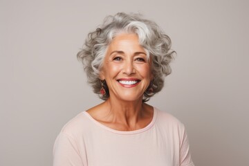 Portrait of a smiling senior woman with grey hair posing against grey background