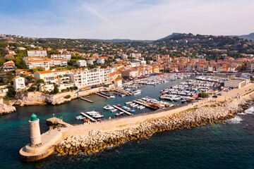 Picturesque aerial view of Cassis cityscape on Mediterranean coast overlooking marina with moored yachts and lighthouse on sunny autumn day, Southern France