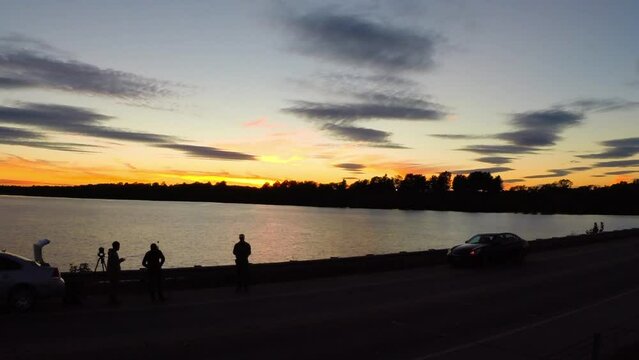 Aerial: Drone Downward Shot Of Silhouette Of People Watching Rippled River During Tranquil Sunset - Buckner, California