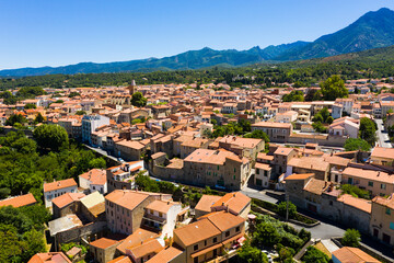 Scenic drone view of Prades summer cityscape surrounded by mountains overlooking bell tower of Saint-Pierre Church, Pyrenees-Orientales, France