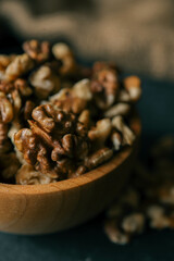 Walnuts in a wooden plate on a dark background