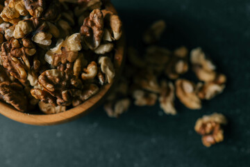 Walnuts in a wooden plate on a dark background