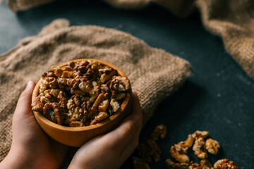 Walnuts in a plate in hands on a dark background
