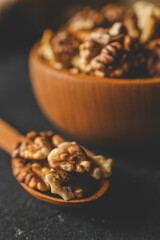 Walnuts in a wooden plate on a dark background