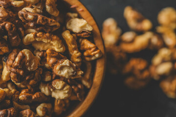 Walnuts in a wooden plate on a dark background