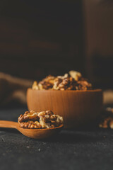Walnuts in a wooden plate on a dark background