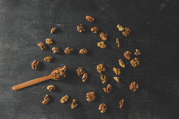Walnuts in a wooden spoon on a black background