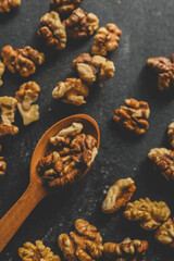 Walnuts in a wooden spoon on a black background