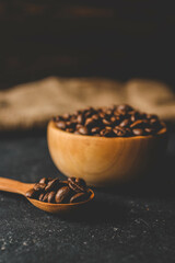 Coffee beans in a wooden plate on a black background