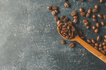 Coffee beans pour out from a wooden spoon on a retro background, top view