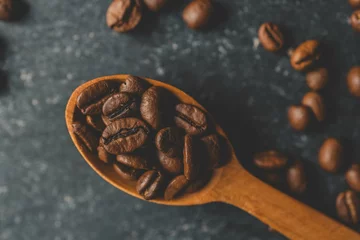 Fotobehang Coffee beans pour out from a wooden spoon on a retro background, top view © shine.graphics
