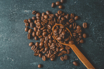 Coffee beans pour out from a wooden spoon on a retro background, top view