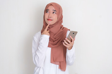 Fototapeta premium Moslem Asian woman thinking about something while holding mobile phone