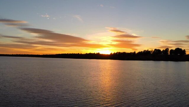 Aerial: Drone Panning Beautiful Shot Of Rippled River Water By Trees Under Orange Clouds At Sunset - Buckner, California