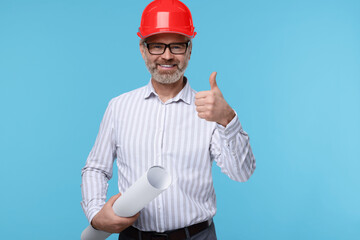 Architect in hard hat holding draft and showing thumb up on light blue background