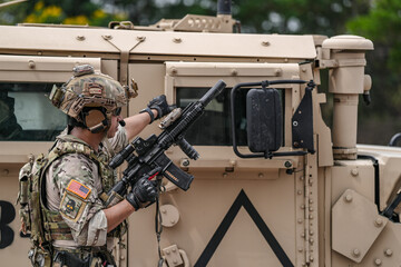 Confident soldier in full gear stands before a military vehicle, rifle in hand, showcasing...