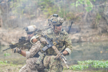 Fototapeta premium Soldiers in tactical gear aiming guns during a military exercise, showcasing teamwork and defense strategies.