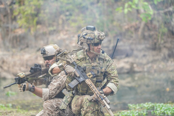 Fototapeta premium Soldiers in tactical gear aiming guns during a military exercise, showcasing teamwork and defense strategies.