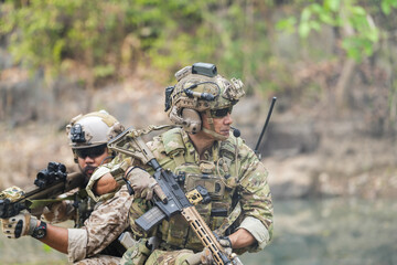Soldiers in tactical gear aiming guns during a military exercise, showcasing teamwork and defense...