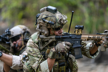Soldiers in tactical gear aiming guns during a military exercise, showcasing teamwork and defense...
