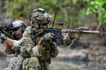 Fototapeta premium Soldiers in tactical gear aiming guns during a military exercise, showcasing teamwork and defense strategies.