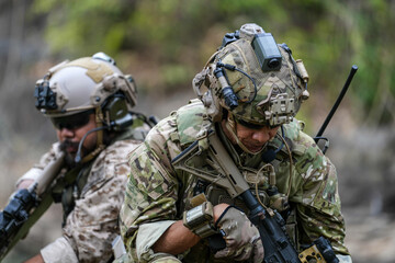 Soldiers in tactical gear aiming guns during a military exercise, showcasing teamwork and defense...