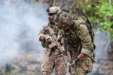 Fototapeta premium Soldiers in tactical gear aiming guns during a military exercise, showcasing teamwork and defense strategies.