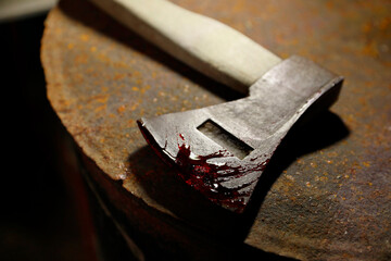 Axe with blood on rusty metal surface, closeup