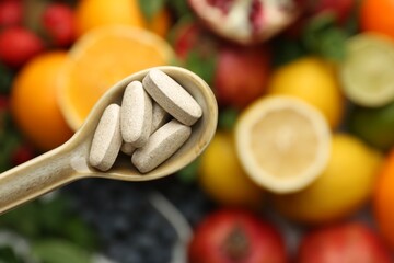 Vitamin pills in spoon over fresh fruits, top view. Space for text