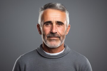 Handsome middle age man with grey beard over grey background.