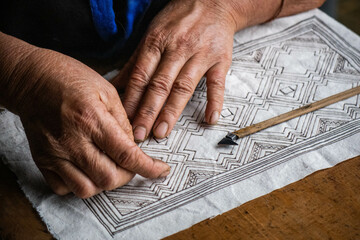 A Flower Hmong woman draws a pattern for her traditional embroidery, Mu Cang Chai, Yen Bai, Vietnam