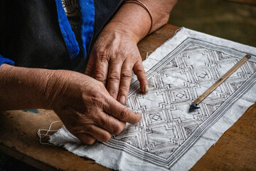 A Flower Hmong woman draws a pattern for her traditional embroidery, Mu Cang Chai, Yen Bai, Vietnam