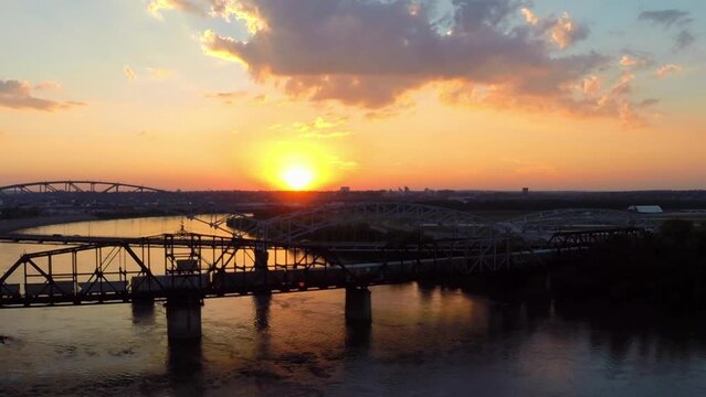 Aerial Silhouette Of Old Chain Of Rocks Bridge, Drone Flying Backwards Over Rippled River During Sunset - Buckner, California