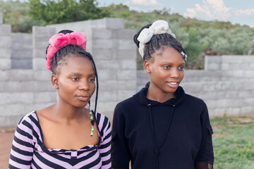 two young african woman, standing in the yard , village life in south africa