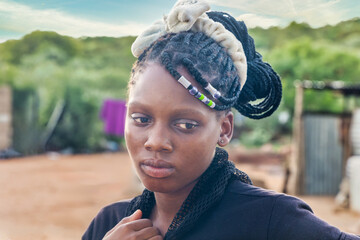 african girl with braids in an african village in Botswana, view from the backyard