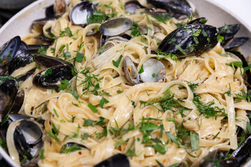 Homemade tagliatelle (spaghetti, linguine) with fresh seafood (clams and mussels), white wine creamy sauce, and fresh herbs on top of it