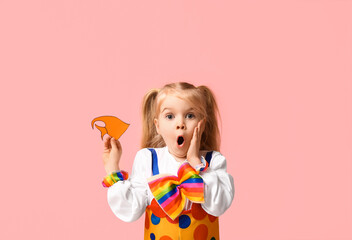 Surprised little girl in clown costume with paper fish on pink background