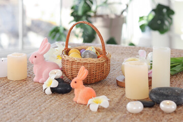 Easter eggs with toy rabbits and flowers on table in spa salon, closeup