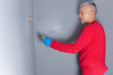 A builder worker applying waterproofing paint to the bathroom wall and floor. Applying...