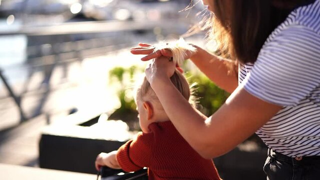 Mom combs her little daughter and ties her ponytail on top. High quality 4k footage