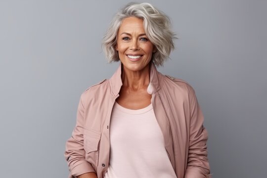 Portrait of a happy mature woman smiling at camera against grey background