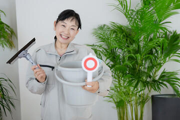 笑顔で清掃具を持った中高年女性