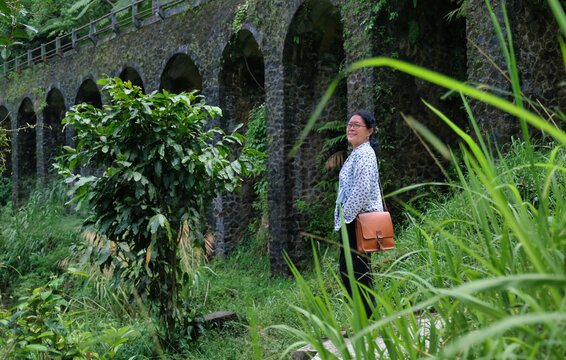 Woman exploring the nature under old concrete bridge of Plunyon, Yogyakarta