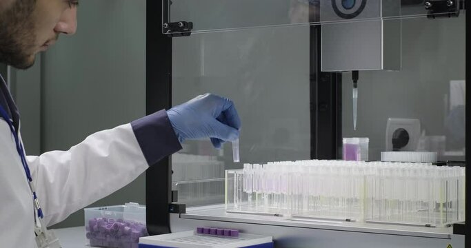 Vaccines, chemicals, medicines development. Scientist or chemist closes tubes with lids. Robotic arm in a laboratory pours purple liquid into test tubes