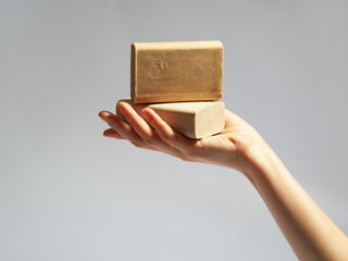 female women washing her hand with soap on grei gradient background. laundry soap in hand