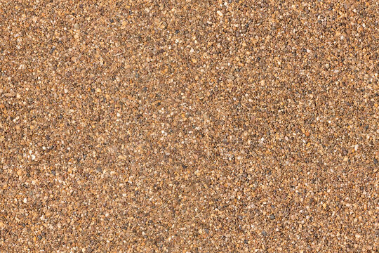An aerial view of a large, stony surface ground texture. Image is ready to be tiled to create a much larger image or higher resolution background of a detailed sandy pebble aggregate floor.