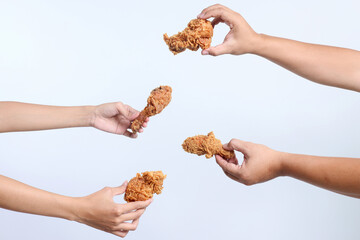 Portrait of many hands holding a piece of fried chicken isolated over white background