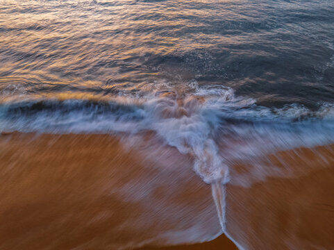 Sunrise, surf and the beach from above with a rip current