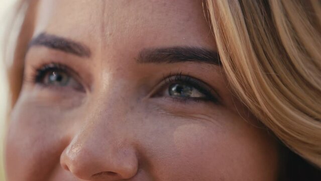 Close up shot of face of woman standing outside smiling at camera with focus on her eyes - shot in slow motion